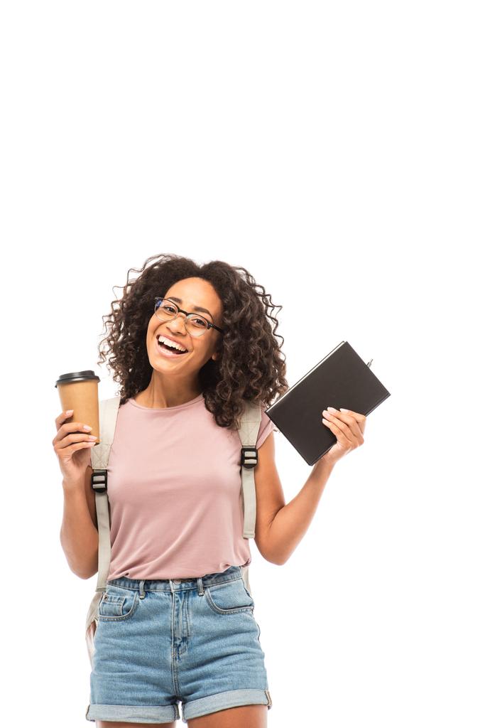 Estudante afro-americano em óculos segurando café para ir e notebook isolado em branco
 - Foto, Imagem