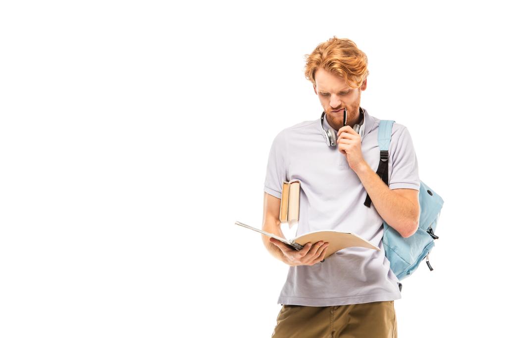 Estudiante pensativo en auriculares con lápiz y mirando el cuaderno aislado en blanco - Foto, Imagen
