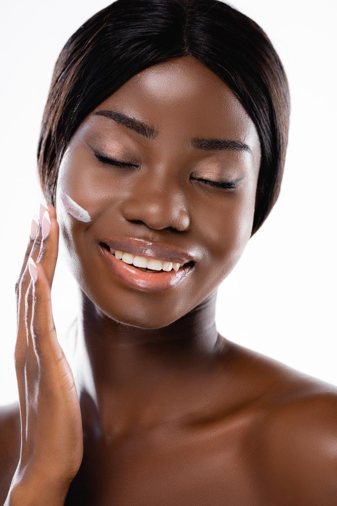 afro-amerikai meztelen nő csukott szemmel kozmetikai krémet az arcon izolált fehér - Fotó, kép
