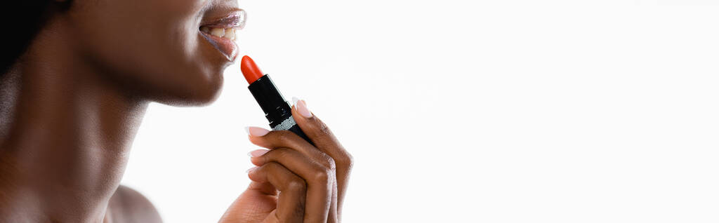 bijgesneden beeld van Afrikaans Amerikaanse naakte vrouw het aanbrengen van lippenstift geïsoleerd op wit, panoramisch schot - Foto, afbeelding