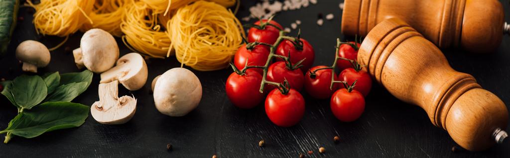 rauwe Italiaanse Capellini met groenten en kruiden op zwarte achtergrond, panoramisch schot - Foto, afbeelding