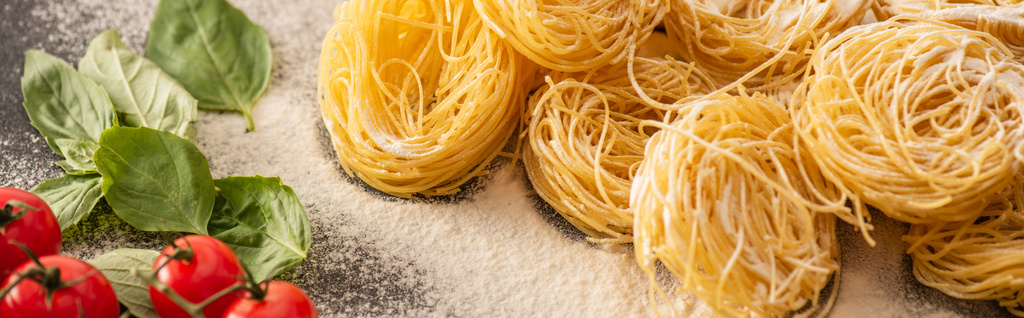 raw Italian Capellini with vegetables and flour on black background, panoramic shot - Photo, Image