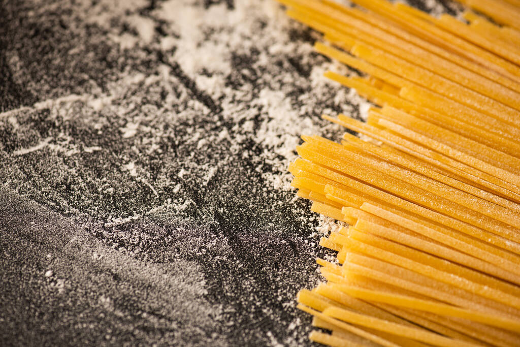закрыть обзор сырых спагетти и муки на черном фоне - Фото, изображение