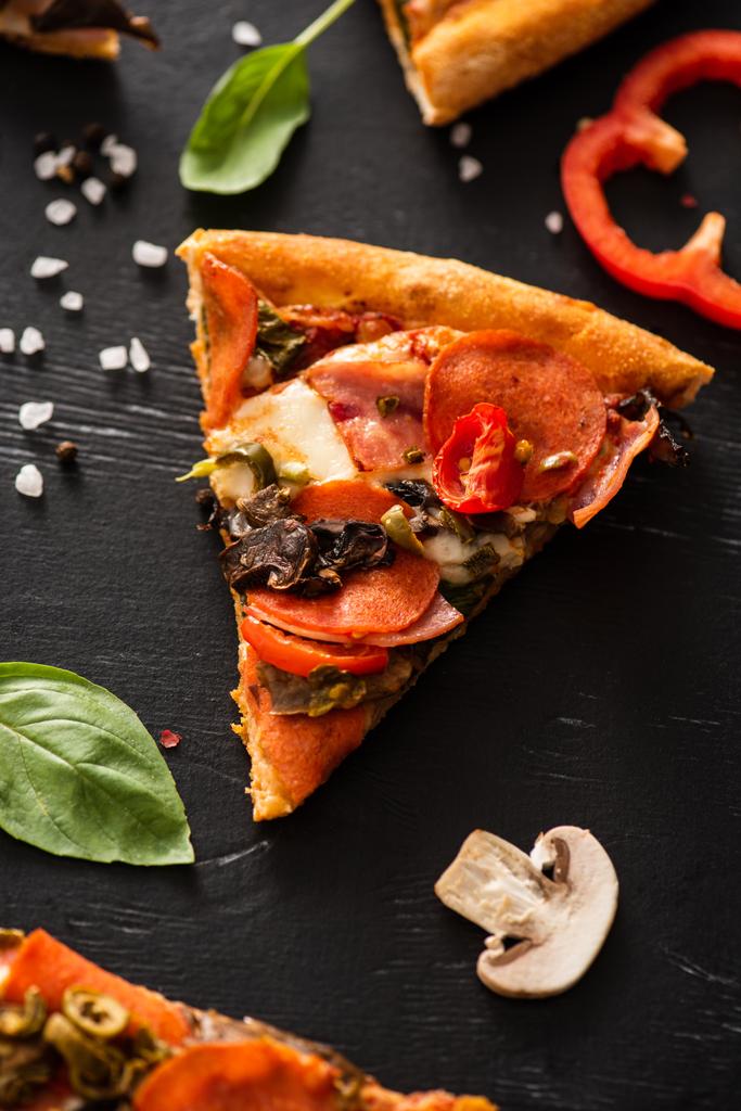 delicious Italian pizza slice with salami near vegetables on black background - Photo, Image