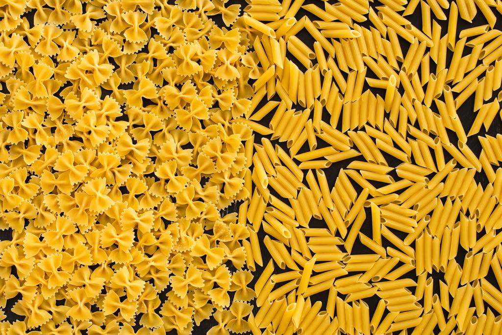 bovenaanzicht van rauwe penne en farfalle pasta - Foto, afbeelding
