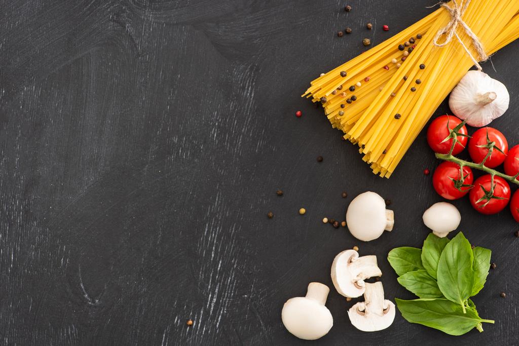 vue du dessus des spaghettis italiens crus aux légumes et aux épices sur fond noir - Photo, image