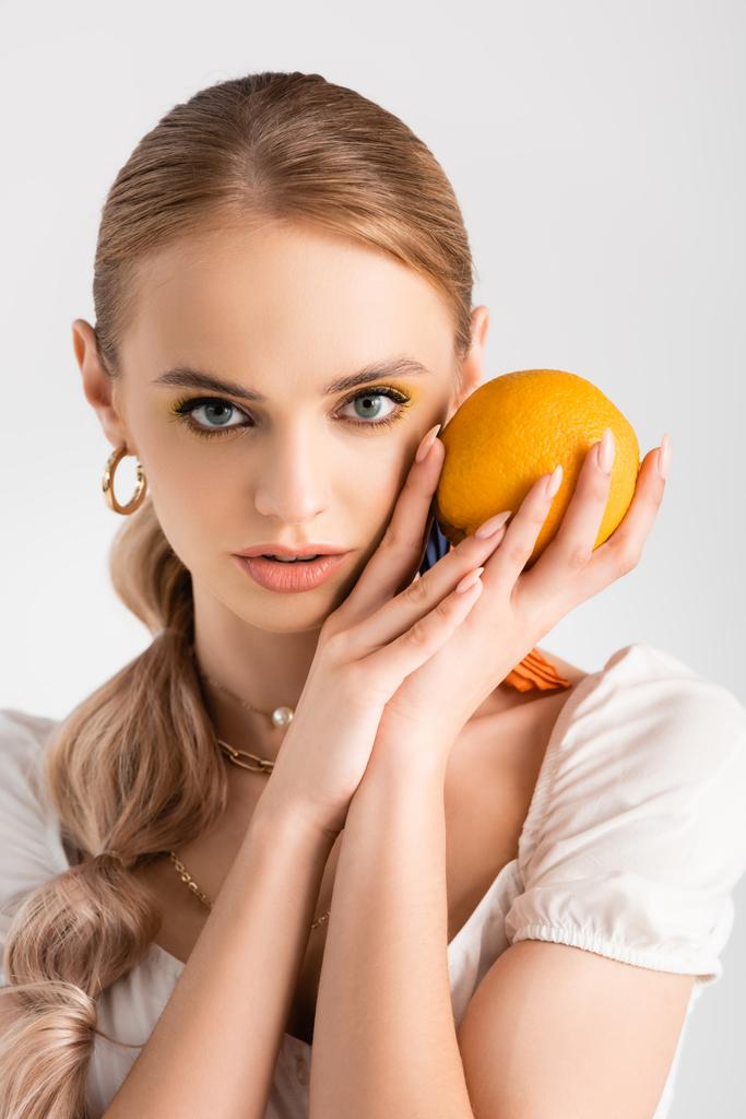 elegancka blondynka pozowanie z pomarańczowy odizolowany na biały - Zdjęcie, obraz