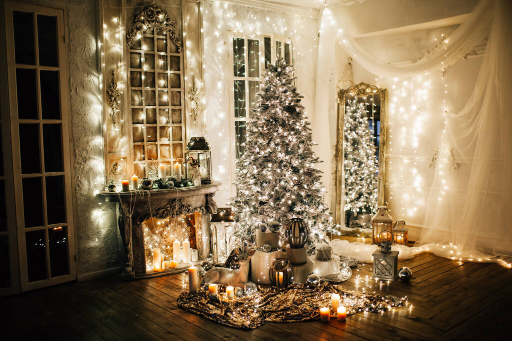 warm and cozy evening in Christmas interior design,Xmas tree decorated by lights presents gifts,toys, deer,candles, lanterns, garland lighting indoors fireplace.holiday living room.magic New year - Zdjęcie, obraz