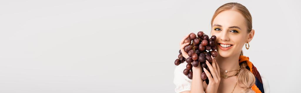 mujer rubia rústica posando con uvas aisladas en blanco, plano panorámico - Foto, imagen