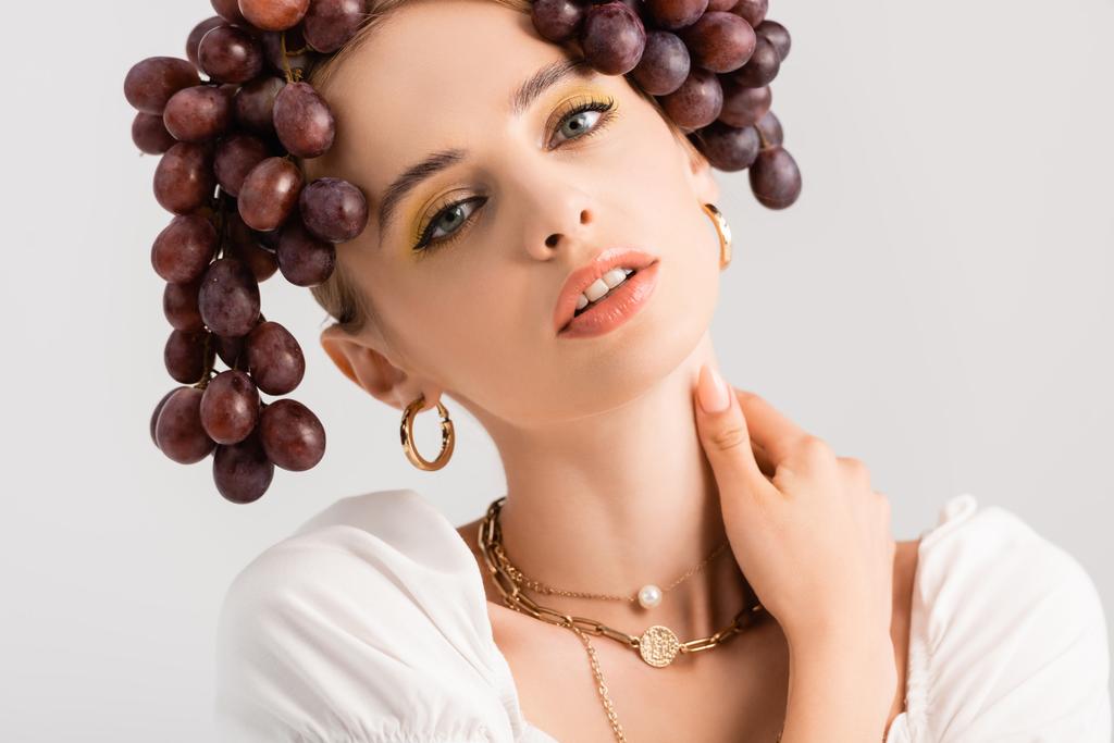 portrait of rustic blonde woman posing with grapes on head isolated on white - Photo, Image