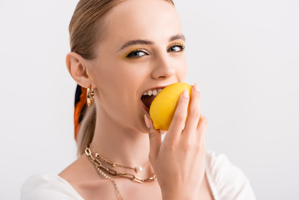 maalaismainen blondi nainen puree keltainen sitruuna eristetty valkoinen - Valokuva, kuva