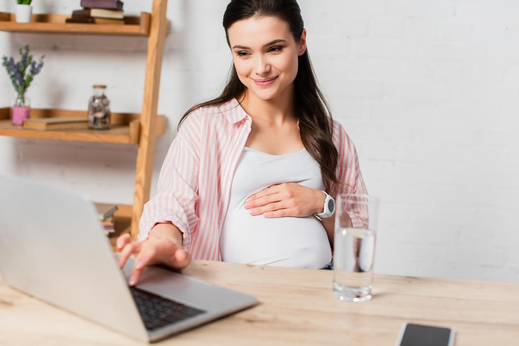 επιλεκτική εστίαση της εγκύου γυναίκα χρησιμοποιώντας φορητό υπολογιστή, ενώ εργάζονται από το σπίτι - Φωτογραφία, εικόνα
