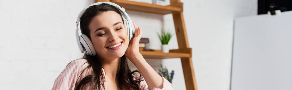 horizontal image of woman with closed eyes listening music in wireless headphones  - Photo, Image