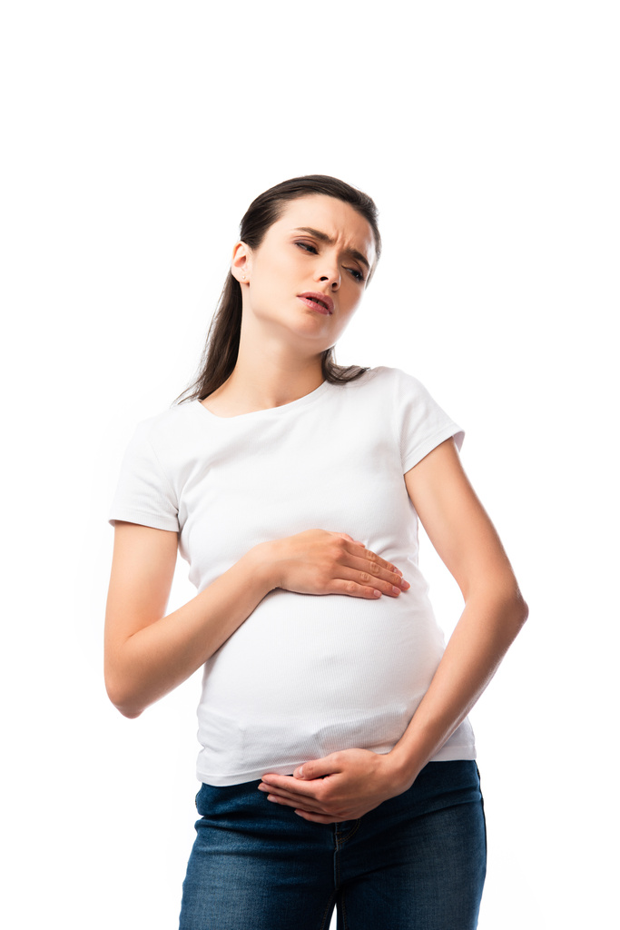 Müde Schwangere in weißem T-Shirt berührt Bauch isoliert auf weiß  - Foto, Bild