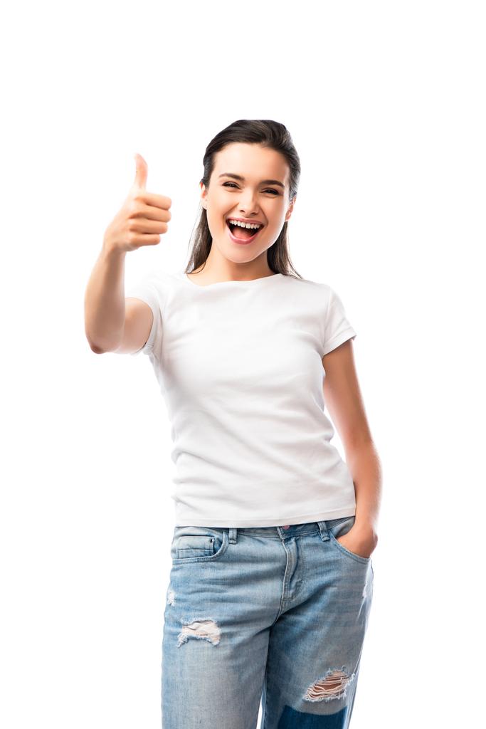 jovem mulher em t-shirt branca e jeans de pé com a mão no bolso e mostrando polegar para cima isolado em branco - Foto, Imagem