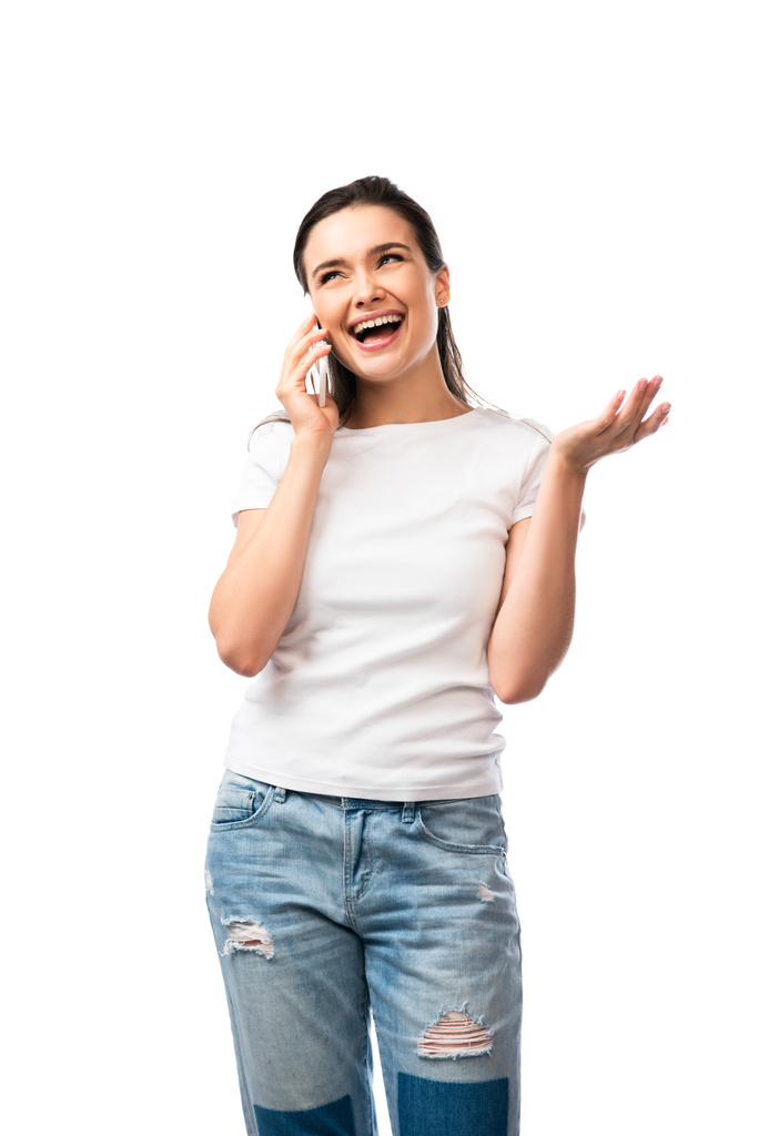 young woman in white t-shirt gesturing and talking on smartphone isolated on white  - Photo, Image