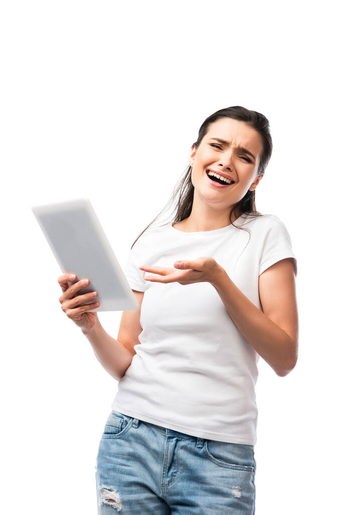 Beyaz tişörtlü kuşkucu kadın beyaz üzerinde izole edilmiş dijital tableti işaret ediyor.  - Fotoğraf, Görsel