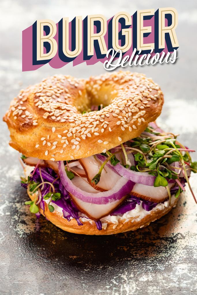 fresh bagel with meat, red onion, cream cheese and sprouts near burger delicious lettering on textured grey surface - Photo, Image