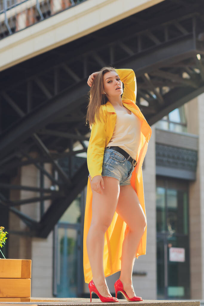 Visualizzazione delle tendenze della moda. Bruna donna attraente postura in giallo brillante soffice mantello. - Foto, immagini