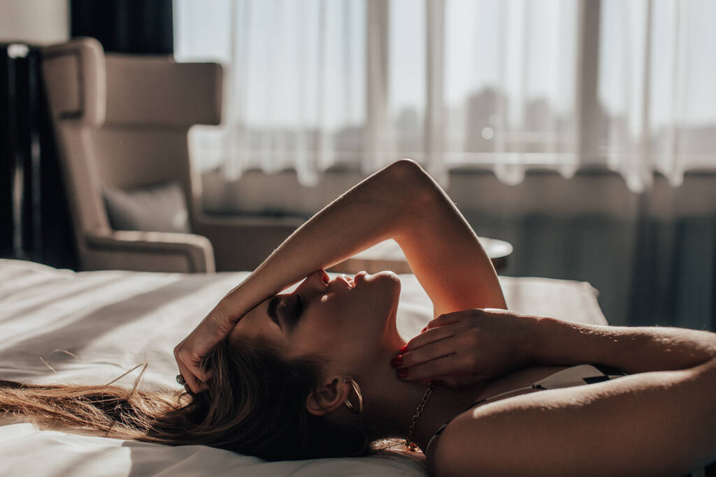 a young beautiful girl, blonde, with bright blue eyes and a beautiful smile and a beautiful face, in a hotel room filled with sunny morning light. - Photo, Image