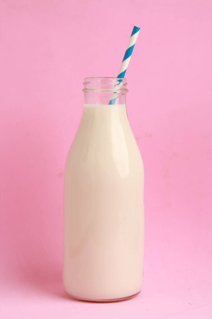Gros plan de lait dans une bouteille en verre sur fond rose - Photo, image