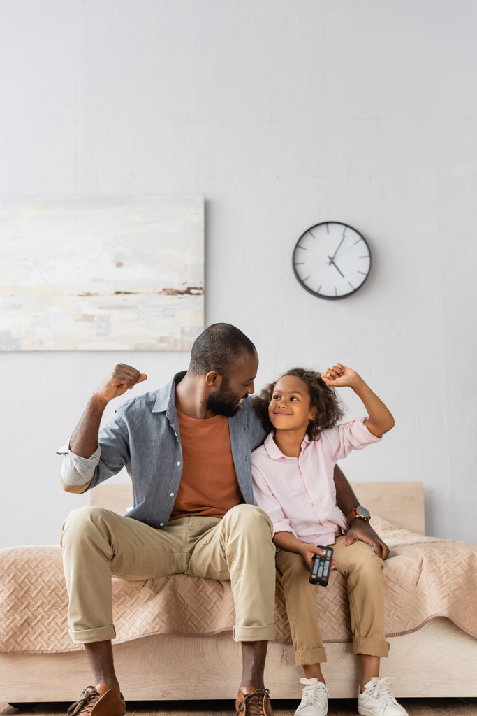 aufgeregter afrikanisch-amerikanischer Vater und Tochter zeigen Siegergeste, während sie sich gegenseitig anschauen - Foto, Bild
