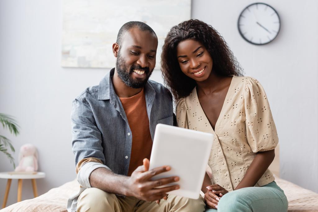 mladý africký americký pár pomocí digitální tablet při sezení v ložnici - Fotografie, Obrázek