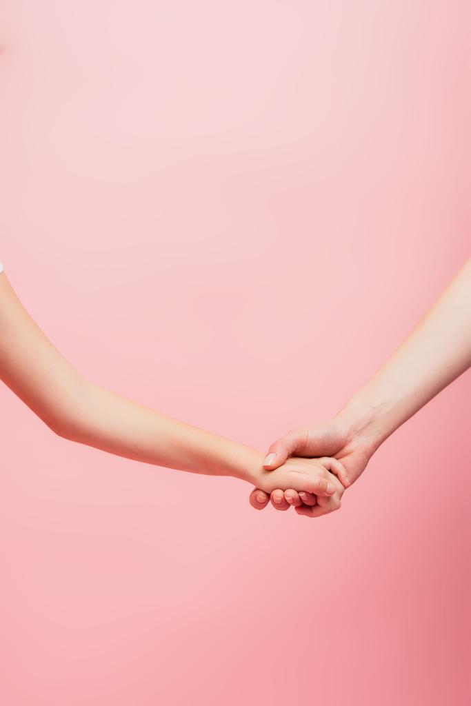 vista parziale della donna e del bambino che si tengono le mani isolate sul rosa con spazio su copia - Foto, immagini