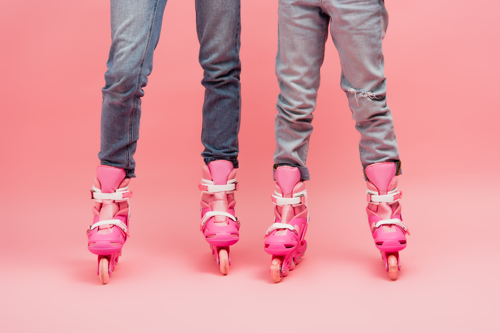 частичный вид матери и ребенка в джинсах и роликовых коньках на розовом - Фото, изображение