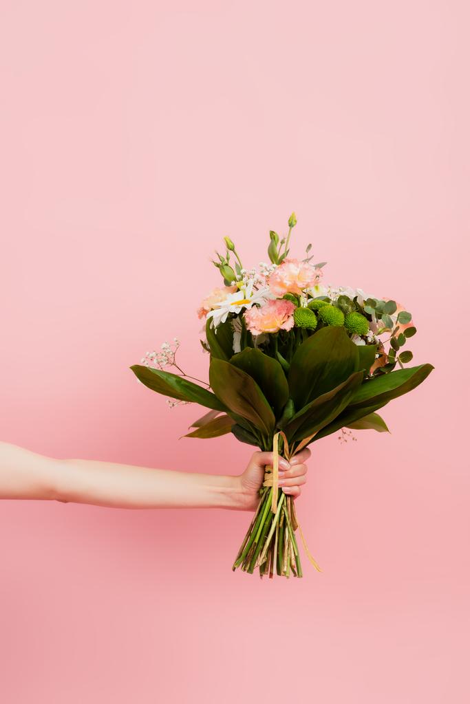 ピンク色に孤立した花の花束を持つ女性のクロップビュー - 写真・画像