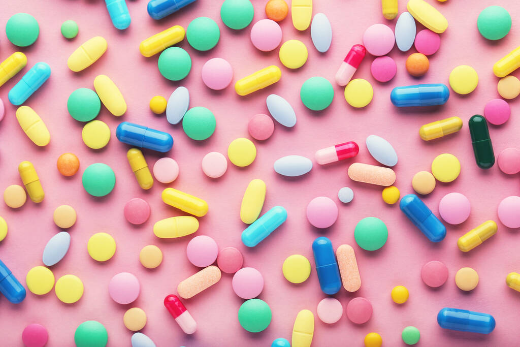 Pillole colorate su sfondo rosa - Foto, immagini