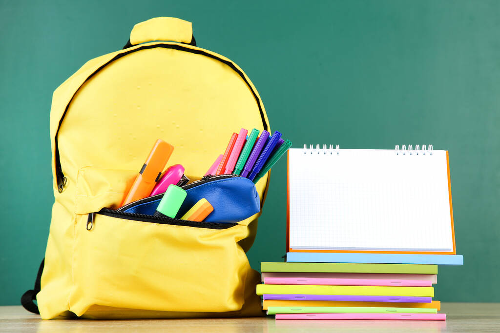 Rucksack mit Schulmaterial und leerem Notizblock auf Tafelhintergrund - Foto, Bild
