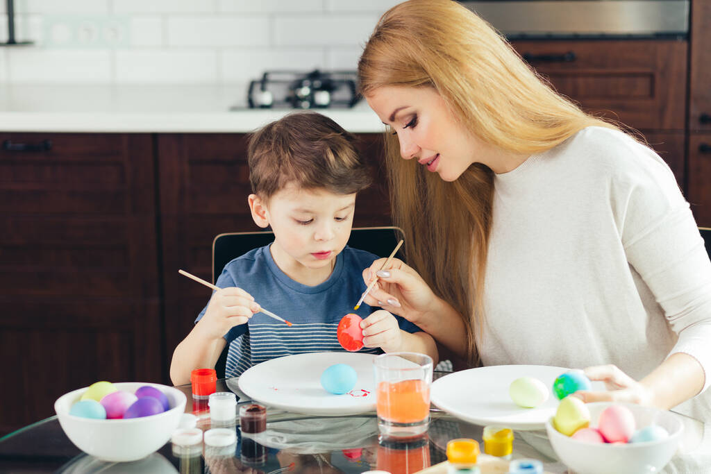 Retrato de jovem feliz pintando ovos de Páscoa com seu adorável filho
 - Foto, Imagem
