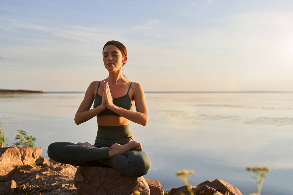 Красивая молодая женщина медитирует на пляже - Фото, изображение