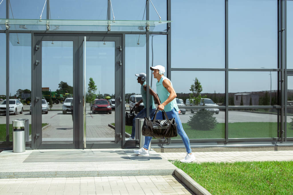 Sport man tegen modern glazen gebouw, luchthaven in megapolis - Foto, afbeelding