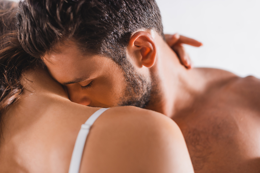 Selektivní zaměření vousatý muž líbání rameno přítelkyně na šedém pozadí  - Fotografie, Obrázek
