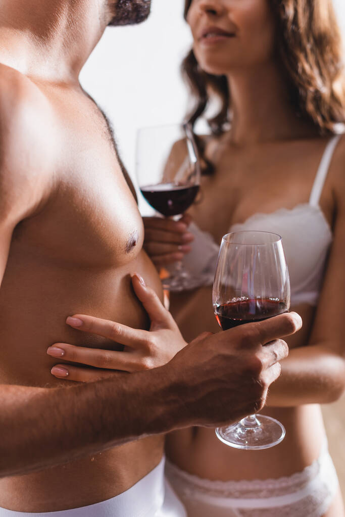 Προβολή σέξυ ζευγαριού με εσώρουχα που κρατάει ποτήρια κρασί στο σπίτι  - Φωτογραφία, εικόνα