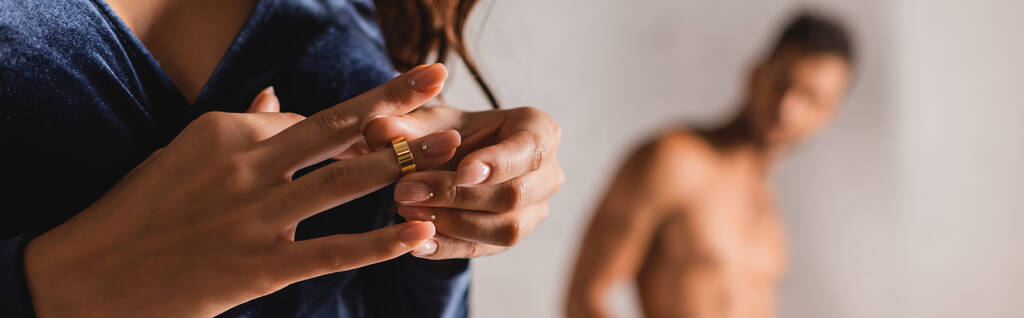Panoramatická orientace ženy svlékání snubní prsten s mužem bez trička v pozadí  - Fotografie, Obrázek