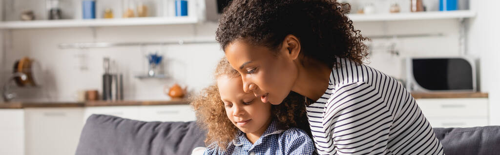 horizontal concept of african american nanny and child sitting together in kitchen - Photo, Image