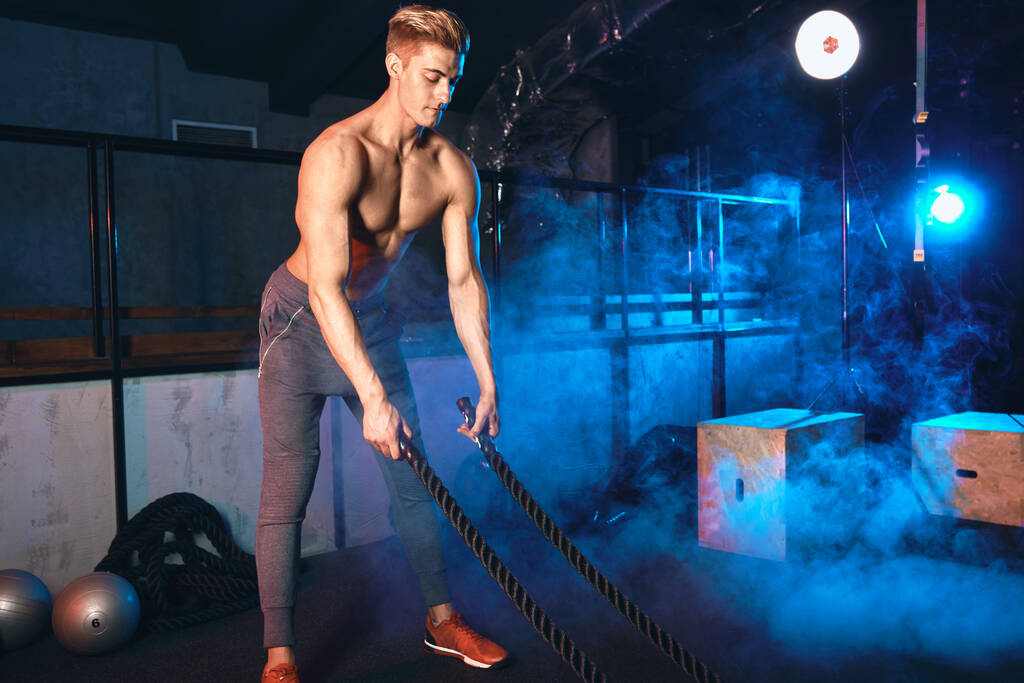 М'язистий потужний чоловік тренується з мотузкою в функціональному тренажерному залі
 - Фото, зображення