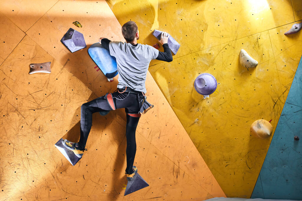 Vista trasera del deportista sin antebrazo escalada pared de roca amarilla en el interior - Foto, imagen