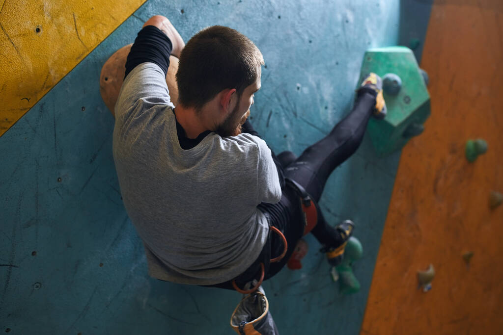 Sportovec pohybující se na umělé skalní stěně, připravuje se na extrémní vrchol hory - Fotografie, Obrázek