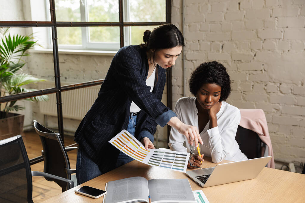 Důvěryhodné seriózní inteligentní ženy podnikatelé pracují na novém startupovém projektu, zatímco sedí u kancelářského stolu - Fotografie, Obrázek
