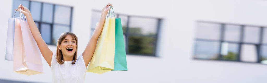 Horizontal crop of woman holding colorful shopping bags on urban street  - Photo, Image