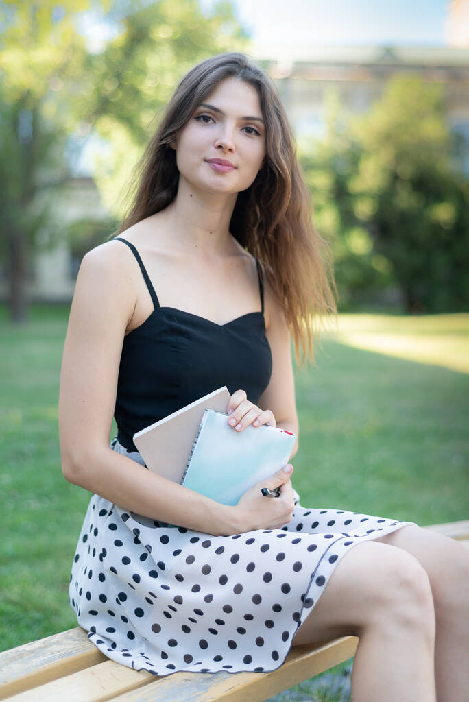 大学の近くのベンチに本とノートを持つ女の子の学生。キエフ。ウクライナ - 写真・画像