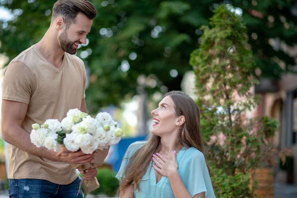 Bearded male presenting flowers to surprised cute female - Photo, Image