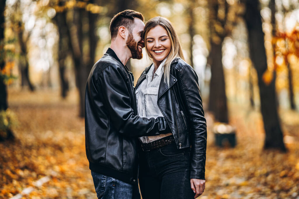 Портрет молодої закоханої пари. Чоловік і жінка обіймаються і посміхаються на тлі осіннього парку
. - Фото, зображення