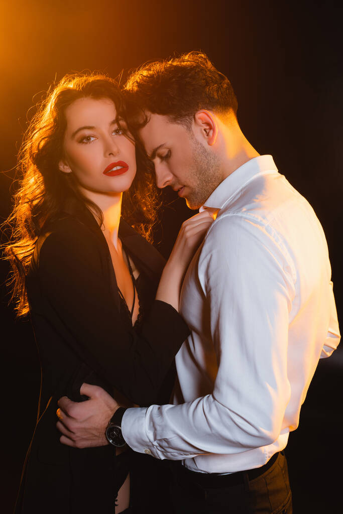 curly woman in jacket touching man in shirt on black  - Photo, Image