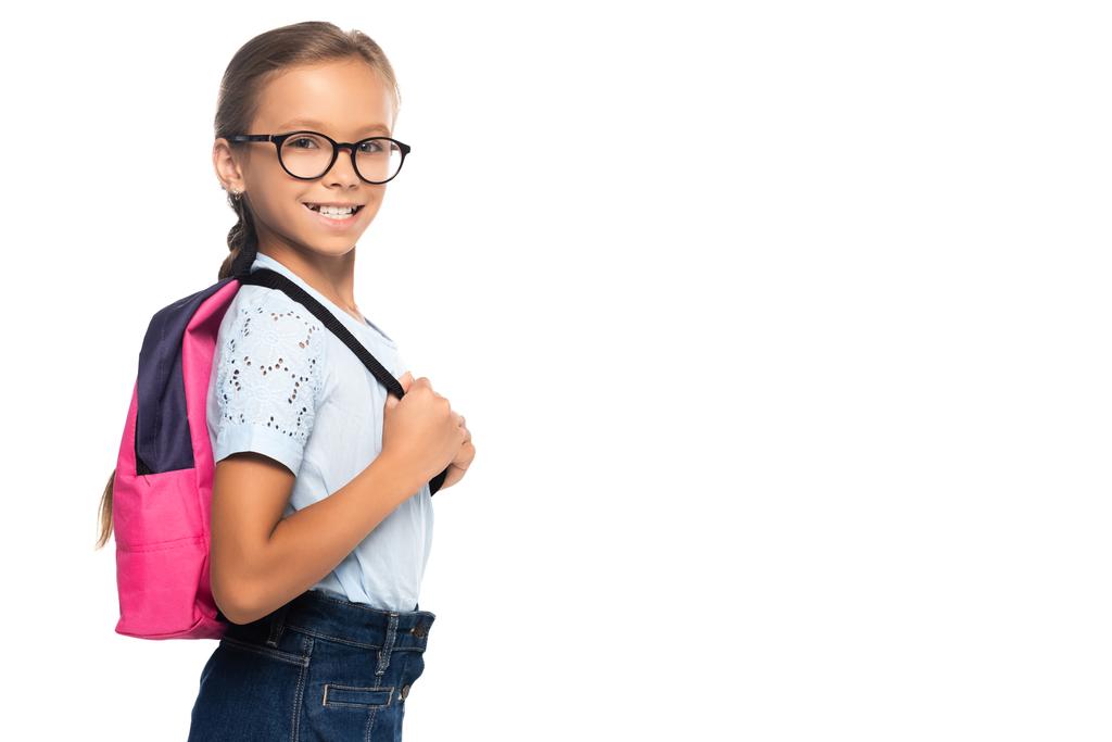 iskoláslány szemüvegben nézi a kamerát, és megérinti hátizsák elszigetelt fehér  - Fotó, kép