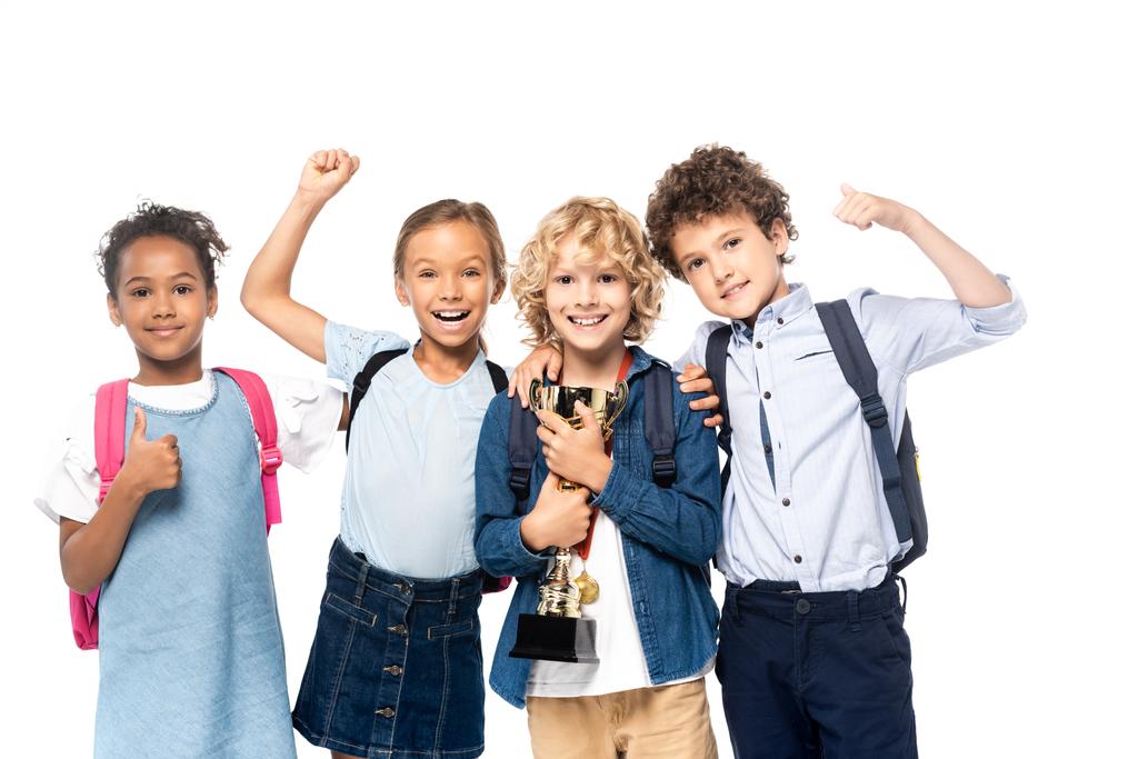 scolari multiculturali festeggiano trionfo vicino ragazzo riccio con trofeo isolato su bianco  - Foto, immagini